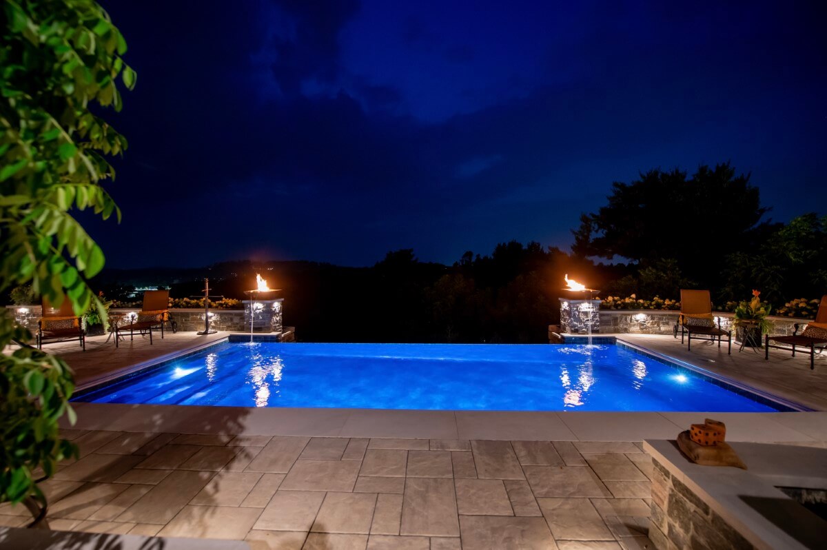Outdoor kitchen, pool, and retreat at night