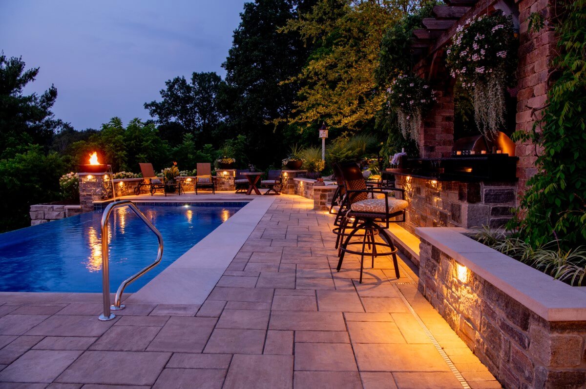 Outdoor kitchen, pool, and retreat at night